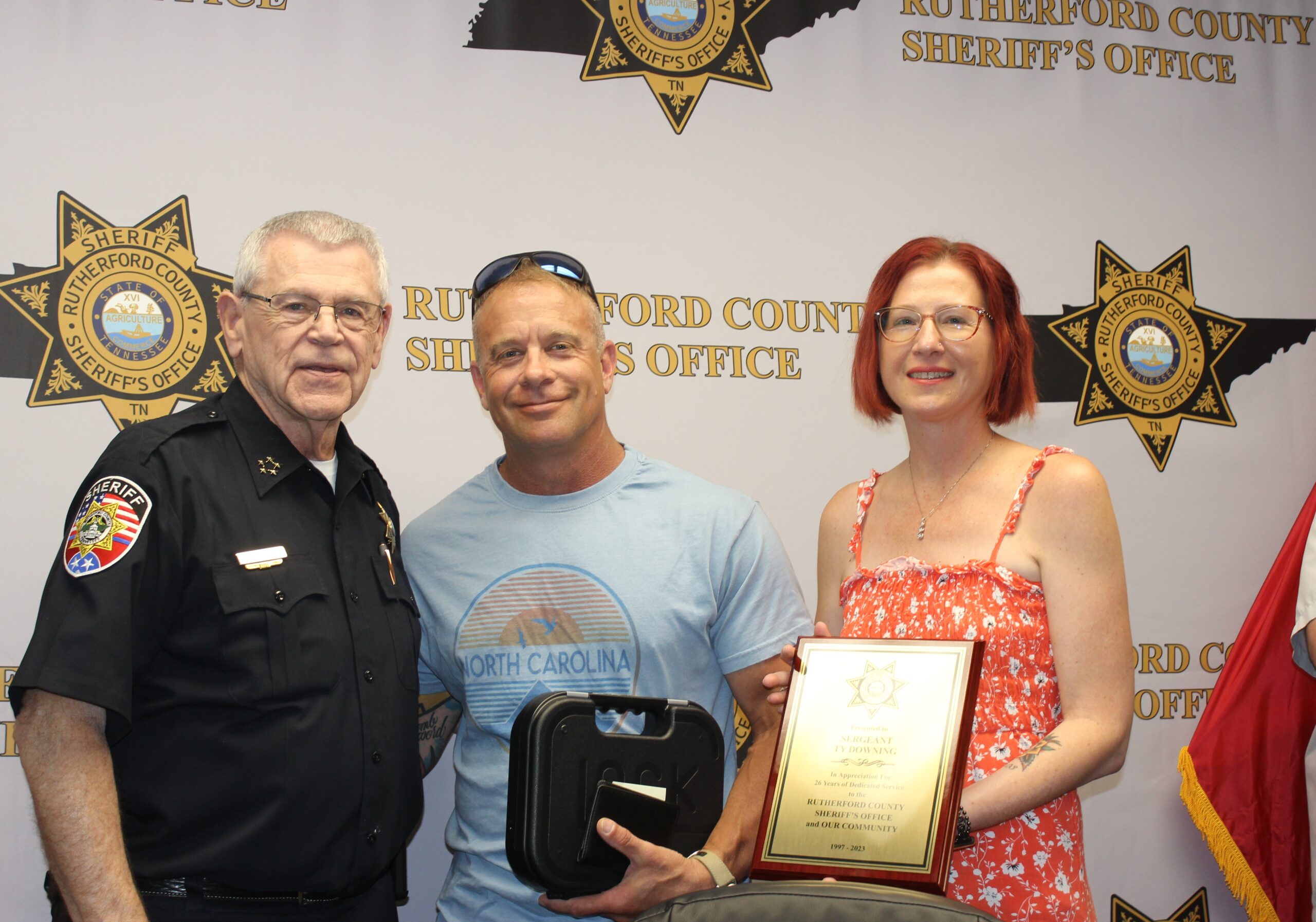 Detective Sgt. Ty Downing is recognized by Sheriff Mike Fitzhugh for retiring after 26 years of service. At right is Downing’s wife, Ericka.