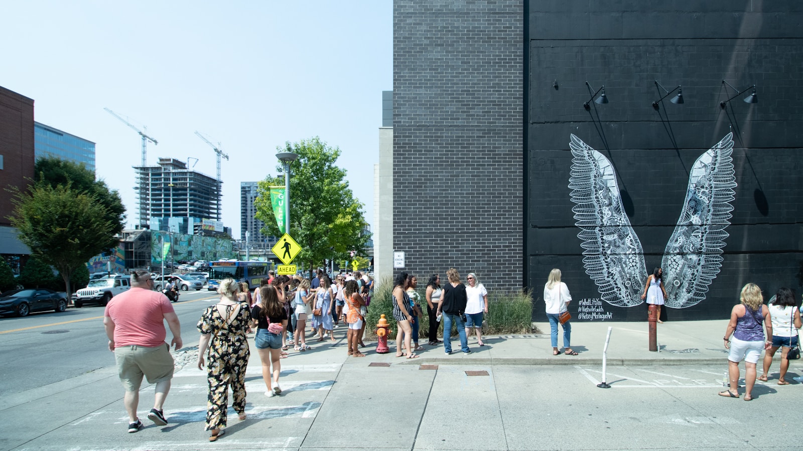 People posing in front of the What Lifts You angel wings mural in Nashville's Gulch neighborhood