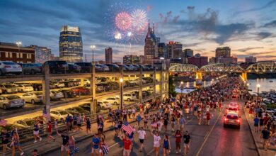 Downtown Nashville parking garage and crowds walking toward Riverfront Park at dusk on the Fourth of July, skyline and early fireworks behind