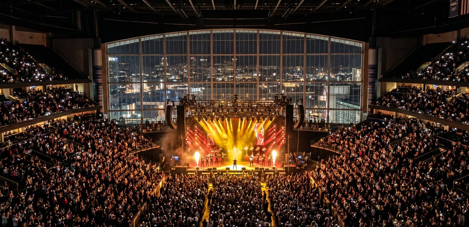 A packed arena concert at Bridgestone Arena in Nashville with gold and red stage lighting