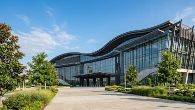 A modern glass convention center on a clear summer morning with Southern landscaping in the foreground