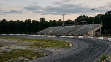 An empty short-track oval speedway grandstand at dusk (illustrative)