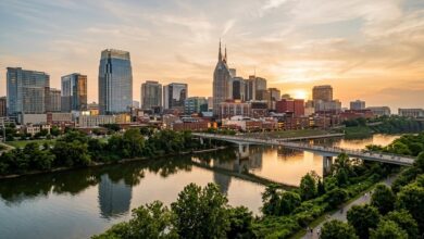 Nashville downtown skyline at golden hour seen across the Cumberland River with a pedestrian bridge (illustrative)