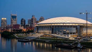 Illustration: a domed riverfront stadium with a translucent roof glowing at dusk against a downtown Nashville skyline. Representative image, not a photograph of the completed building.