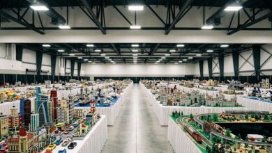 Display tables of large models built from plastic construction bricks running down a convention expo hall aisle (illustrative)