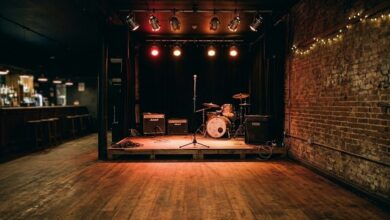 An empty live music club stage with microphone stand and amplifiers under warm stage lighting (illustrative)