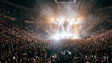 Crowd at an indoor arena rock concert with stage lights (illustrative, AI-generated)