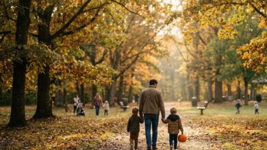 A parent and two children walking a leaf-covered park path in autumn (illustrative)