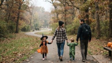 Parents walking with two young children in Halloween costumes on a fall greenway (illustrative)